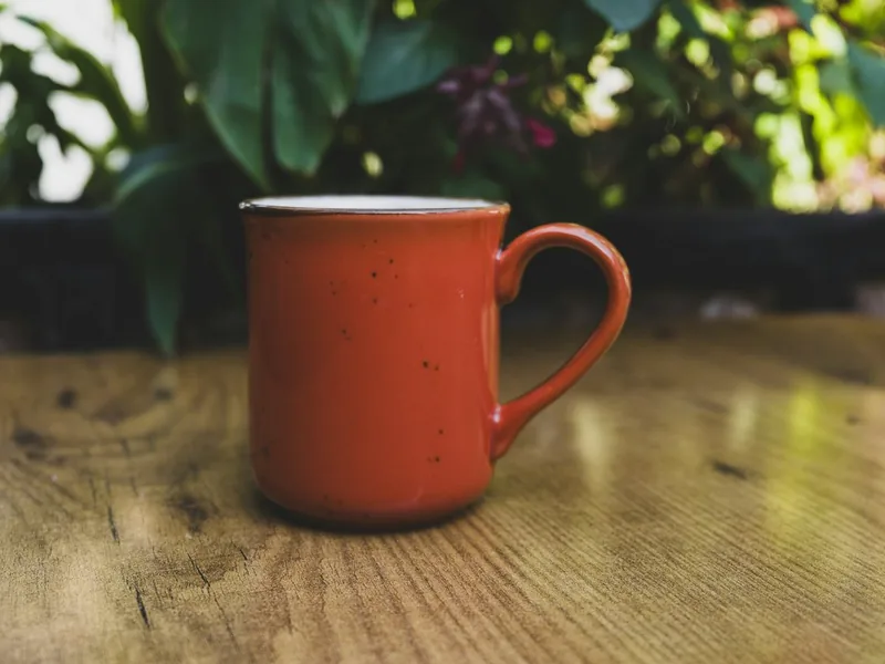A handmade mug on a wooden table, photographed on a phone